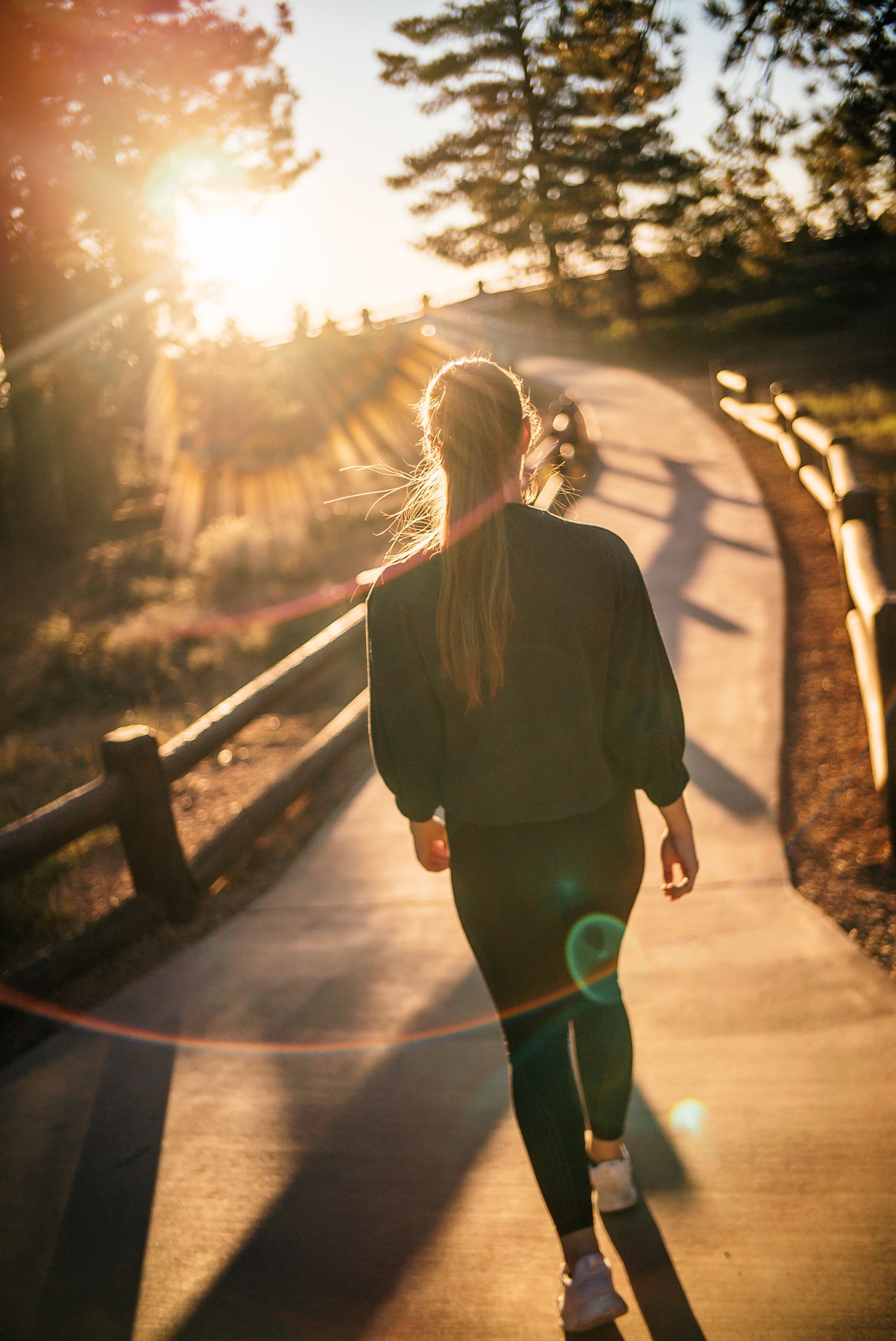Female runner walks along pathway at sunrise