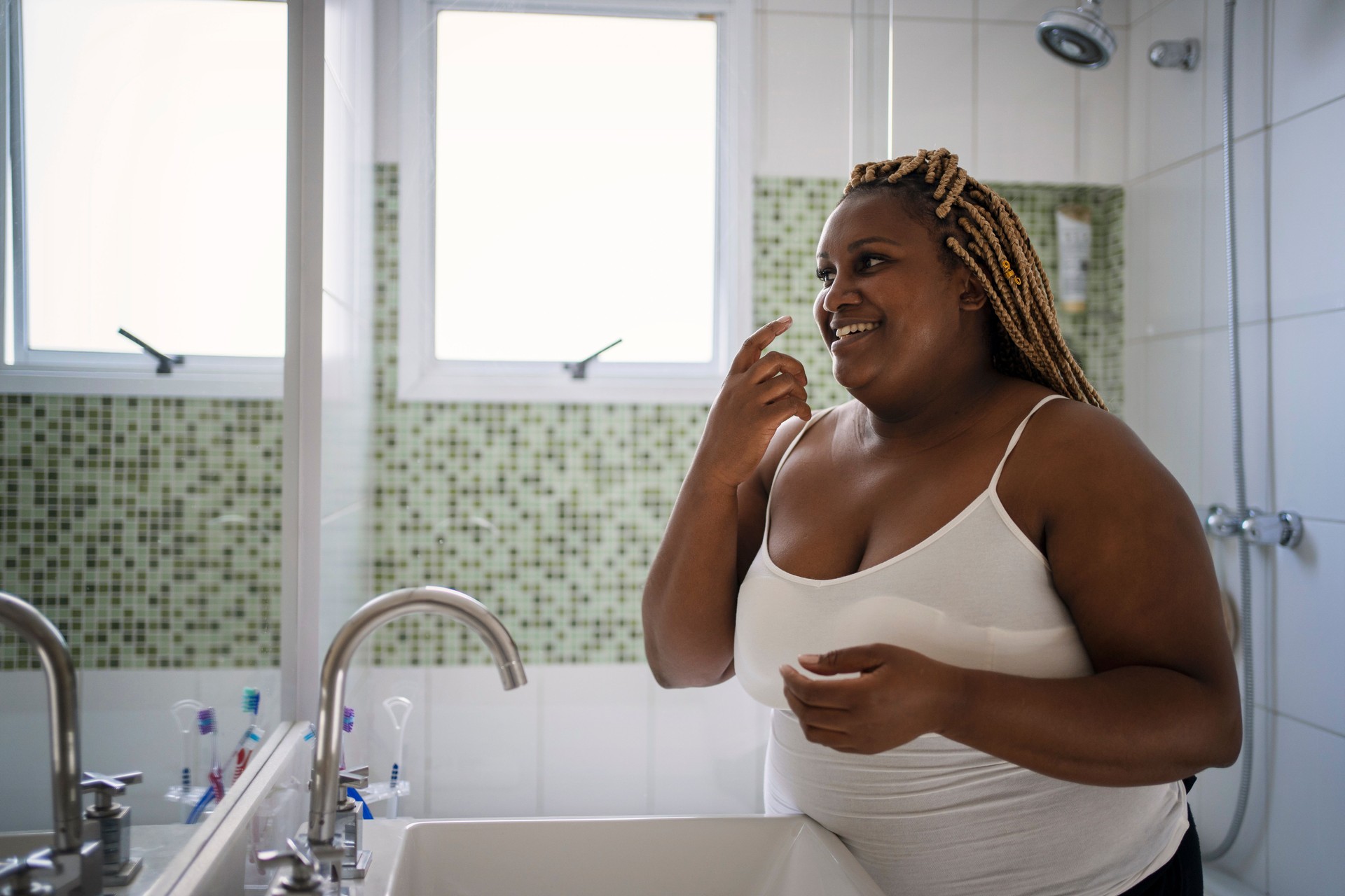 African American woman in her daily skin care routine in the bathroom.